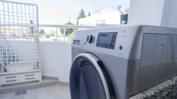 A front view of a front-loading washing machine with a control panel and a digital display.