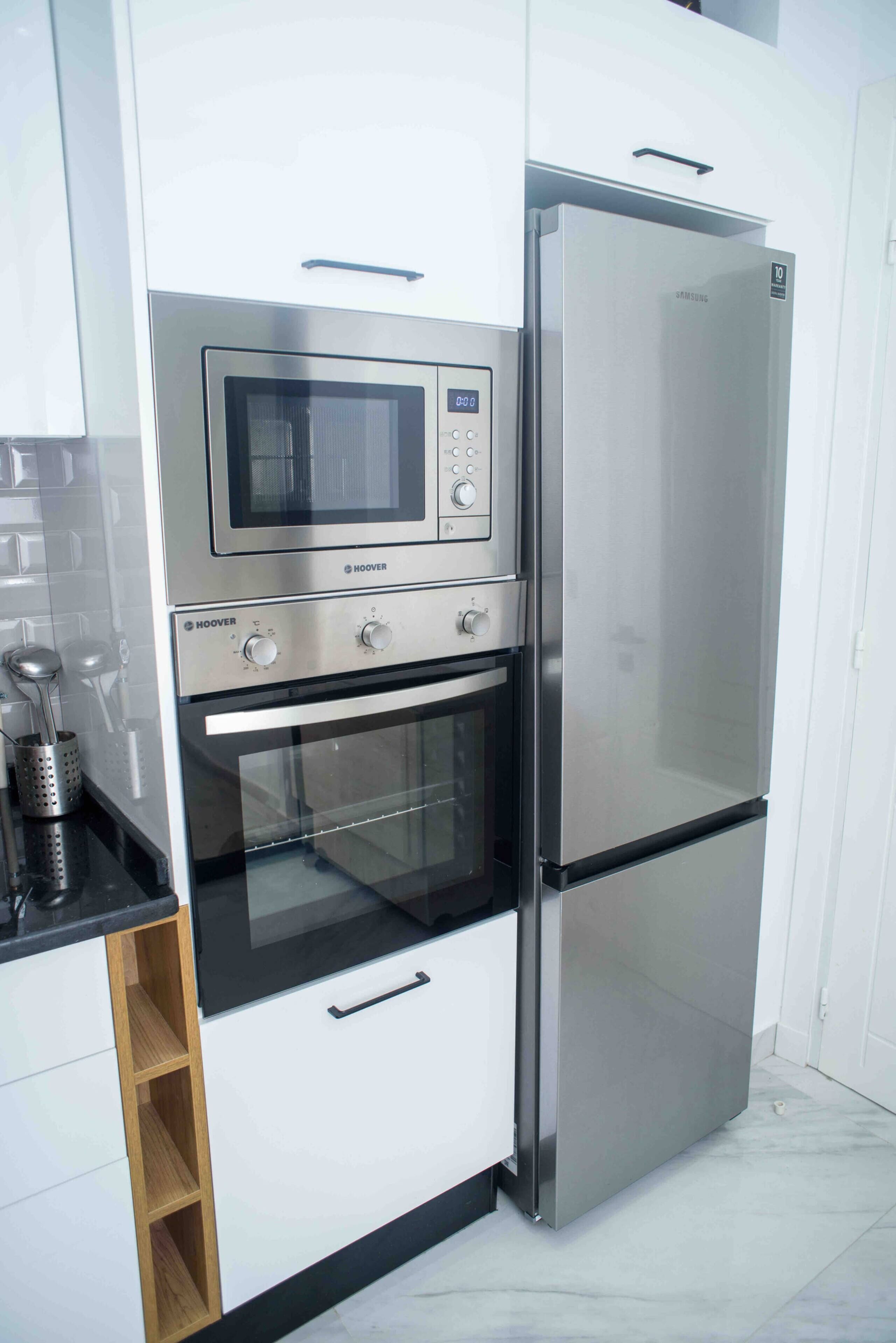 Une cuisine compacte équipée d’un four à micro-ondes, d’un four et d’un réfrigérateur intégrés.