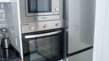 Een kleine keuken met een inbouwmagnetron, oven en koelkast.