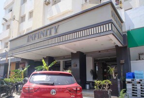 A building with a sign reading 'INFINITY' and a red car parked in front.