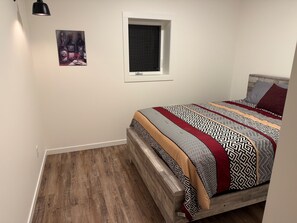 A bedroom with a wooden bed, a window, and a painting on the wall.