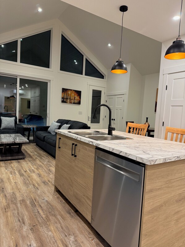 A modern kitchen with a built-in dishwasher, a dining area with a table and chairs, and a large window providing natural light.