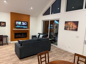 A modern living room with a fireplace, a television, and a large window.