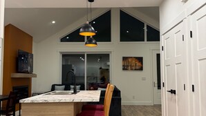 A spacious kitchen with a large island, wooden flooring, and a modern pendant light.