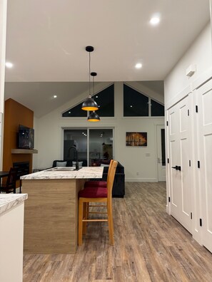 A spacious kitchen with a large island, wooden flooring, and a modern pendant light.