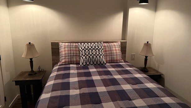 A bedroom with a checkered bedspread, two bedside lamps, and a headboard.