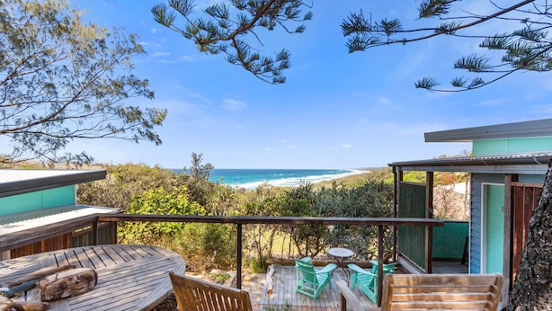 A wooden deck with outdoor seating, overlooking a beach and ocean. - The Headlands Chalets - Cabin 2 (Point Lookout)
