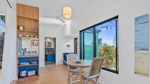A modern kitchen with a dining area, large windows, and a view of greenery. - The Headlands Chalets - Cabin 2 (Point Lookout)