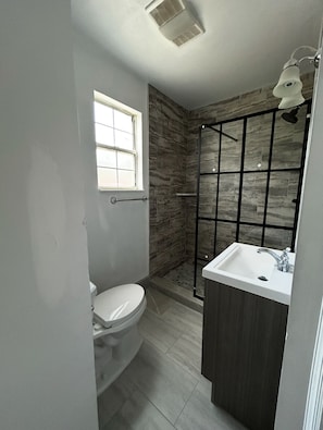 A bathroom with a toilet, a window, a shower enclosure, and a sink. - Stylish Nashville Getaway Near Downtown – Comfort, Convenience & Southern Charm! (Nashville)