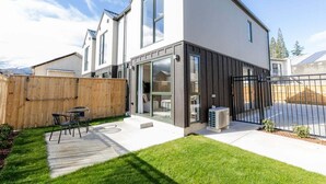 Ein modernes, zweistöckiges Haus mit Terrasse, Holzzaun und schwarzem Metallgitter.