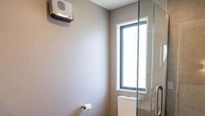 Ein Badezimmer mit Duschkabine aus Glas, Toilette und Waschbecken.