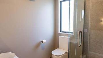 A bathroom with a glass shower enclosure, a toilet, and a sink.