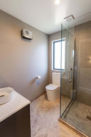 A bathroom with a glass shower enclosure, a toilet, and a sink. - Prime Location | Modern Comfort | Pools - HS7654 (Hanmer Springs)