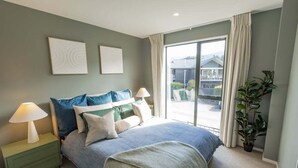 Ein Schlafzimmer mit einem Bett, Nachttischen, einem Fenster und Blick ins Freie.