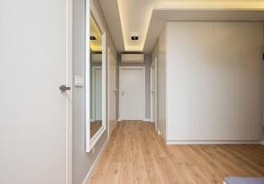 A hallway with wooden flooring, white walls, and a white wardrobe. - Imielin Signature Apartment (Warszawa)