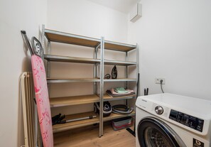 A laundry room with a washing machine, shelves, and a dryer. - Imielin Signature Apartment (Warszawa)