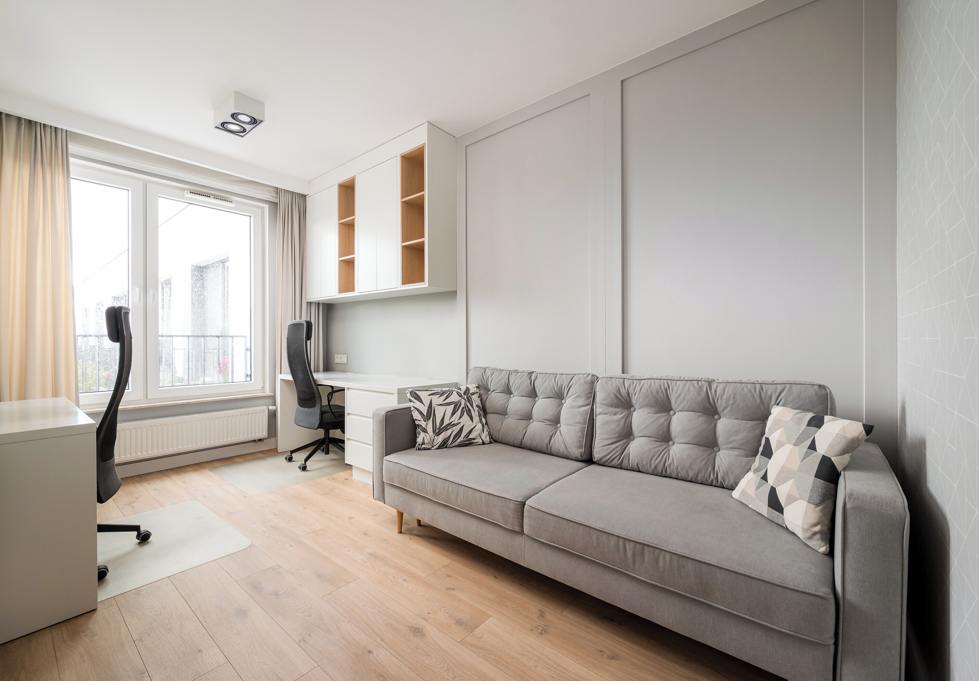 Una sala moderna con un sofá gris, un escritorio y una silla.