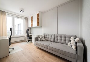 A modern living room with a grey sofa, a desk, and a chair. - Imielin Signature Apartment (Warszawa)