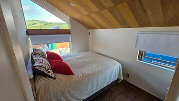 Une chambre à coucher avec un lit, une fenêtre et une vue sur l’extérieur.