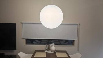 A dining area with a wooden table, white chairs, and pendant lights.