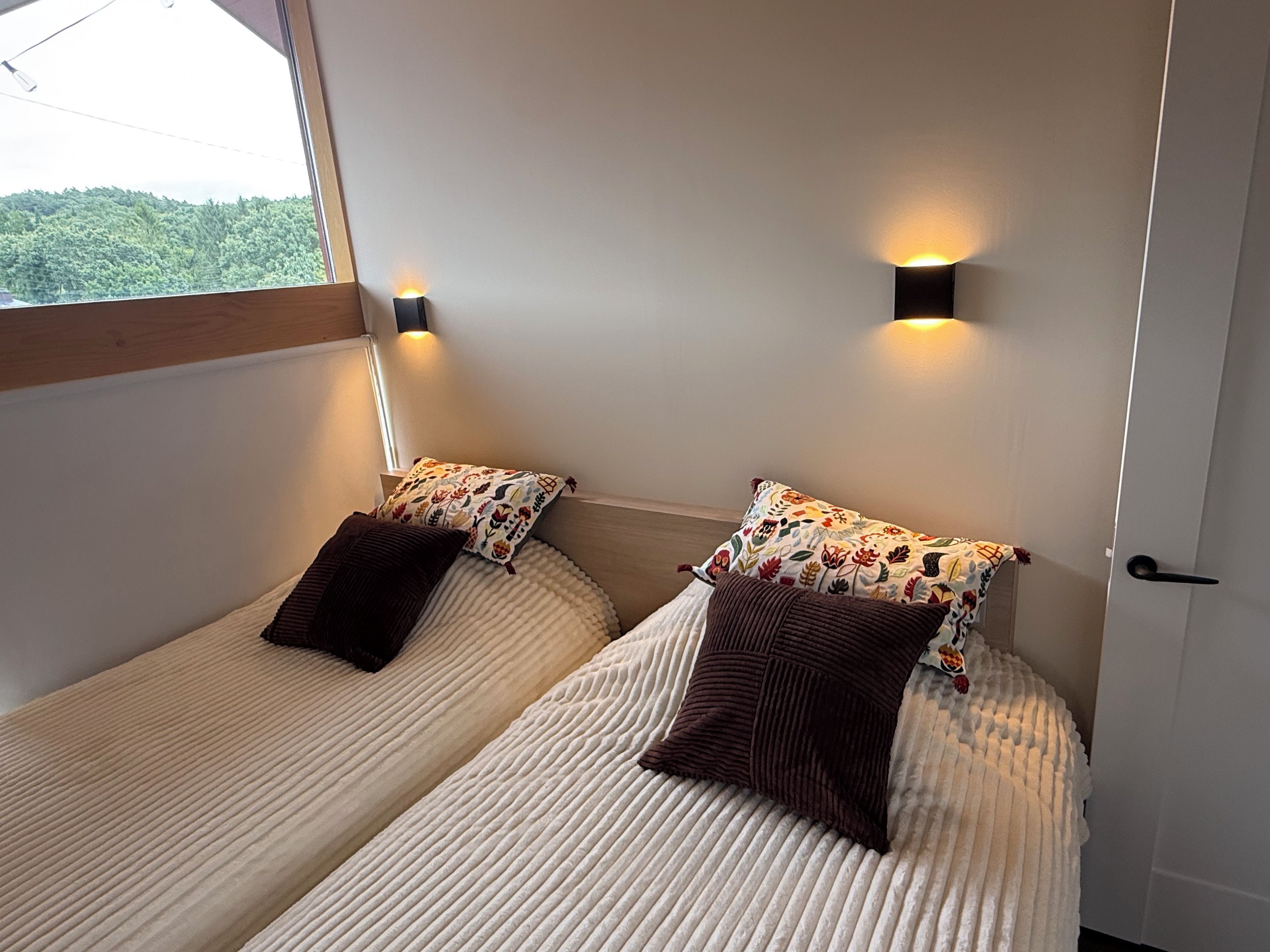 Una habitación con dos camas, cada una con un cojín estampado y una lámpara de pared.