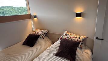 Una habitación con dos camas, cada una con un cojín estampado y una lámpara de pared.
