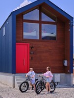 Una cabaña de madera de dos pisos con una puerta roja y una placa con el nombre.