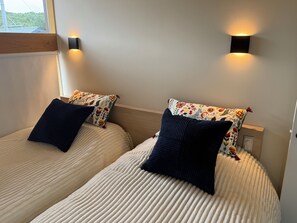 Two twin beds with patterned pillows and wall-mounted lights.