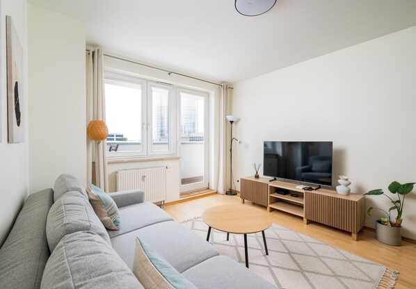Een moderne woonkamer met een bank, televisie en een klein bijzettafeltje.