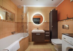 Een moderne badkamer met een bad, toilet, wastafel en douche.