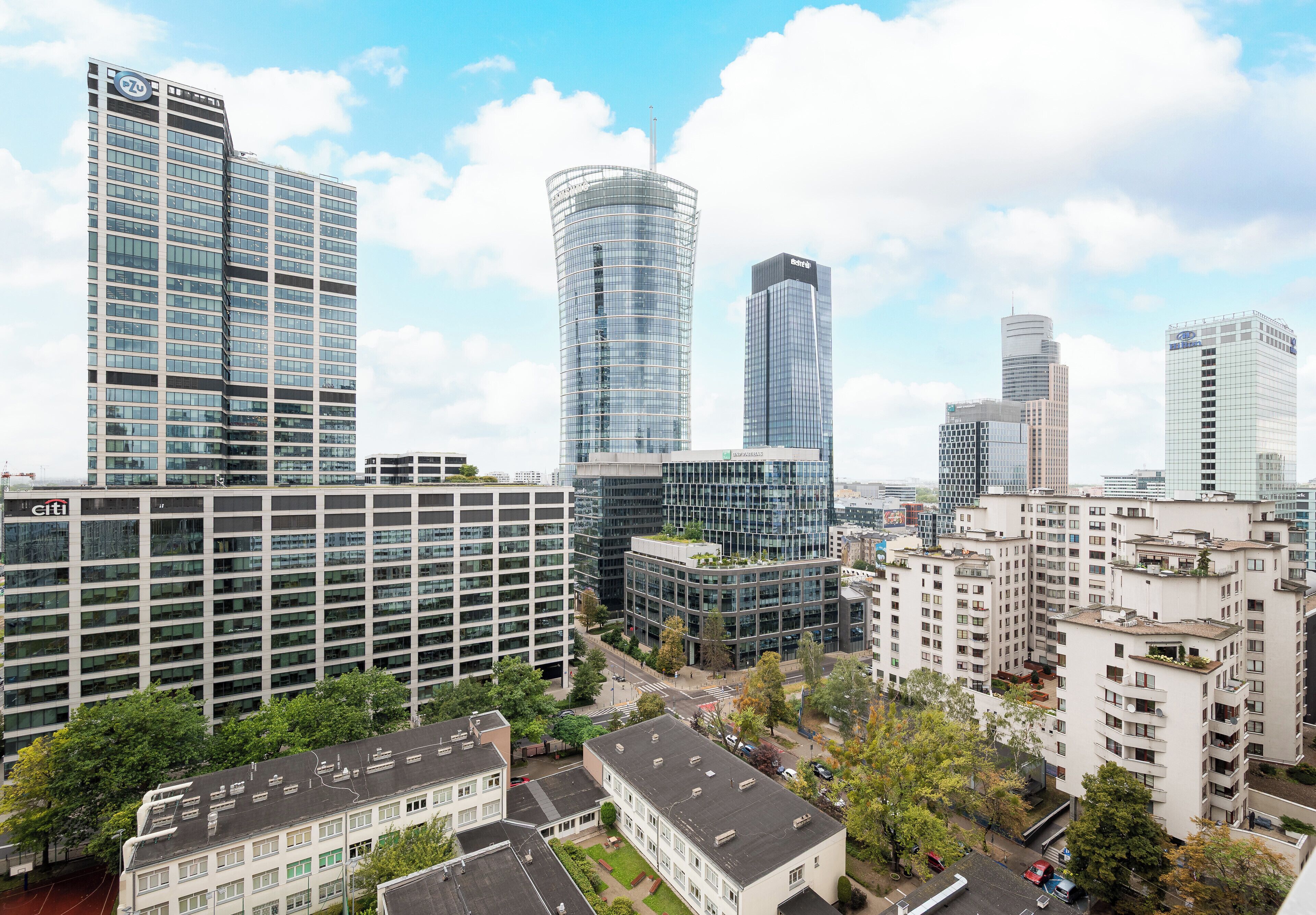 A cityscape with modern high-rise buildings, including a distinctive curved glass tower.