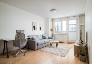Een moderne woonkamer met een grijze bank, een bureau en een vloerlamp.