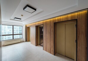 A modern elevator with wood paneling and a visible emergency exit sign. - Łucka 16th Floor Vista Apartment (Warszawa)