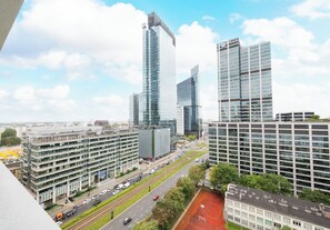 Une vue urbaine avec des bâtiments modernes, un parking à plusieurs niveaux et une route où circulent des véhicules.