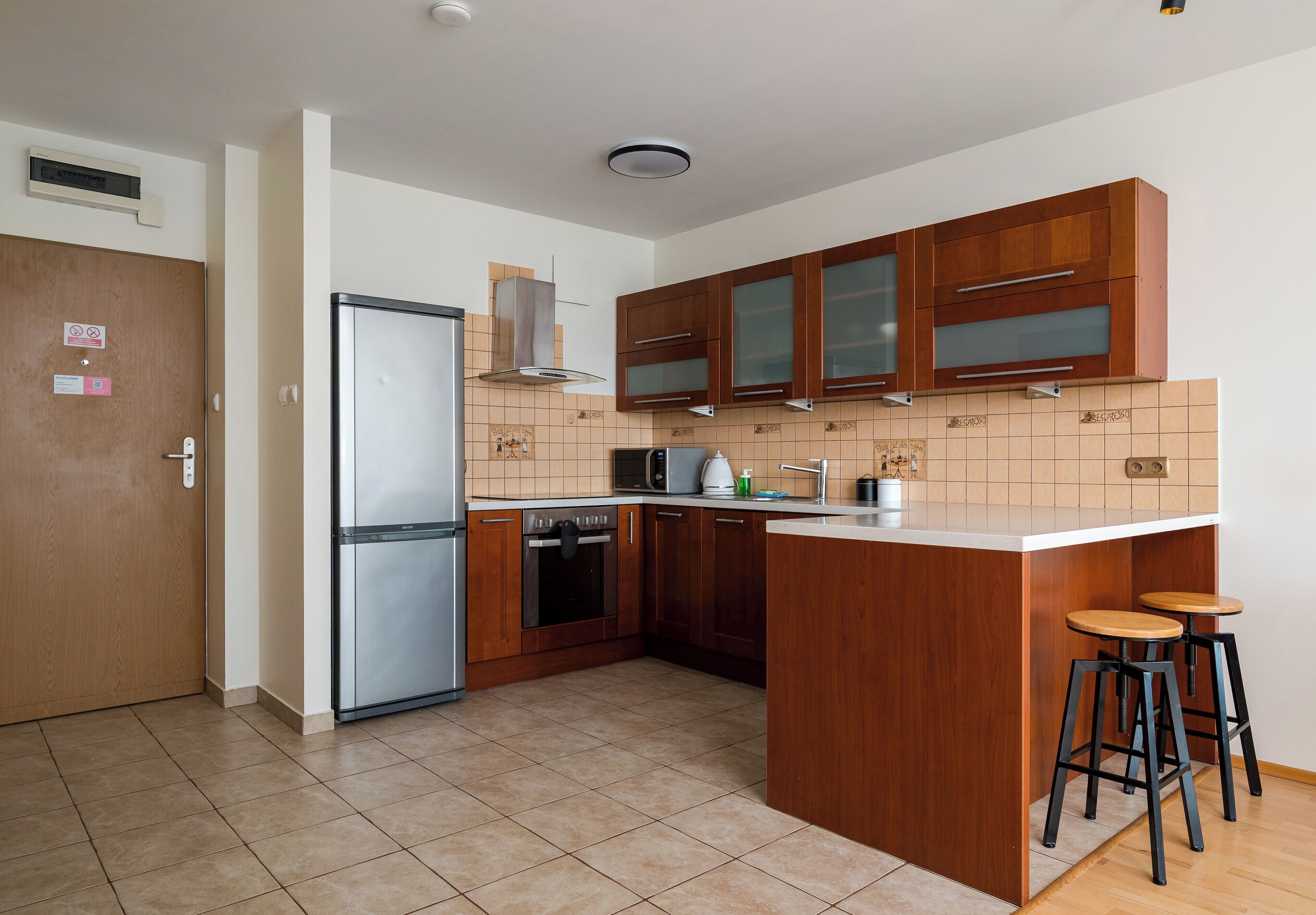 Een moderne keuken met houten kastjes, een roestvrijstalen koelkast, een magnetron en een koffieapparaat.