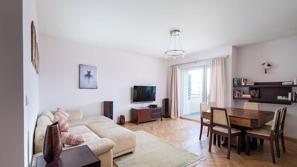 Sala de estar com sofá, televisão e área de jantar.