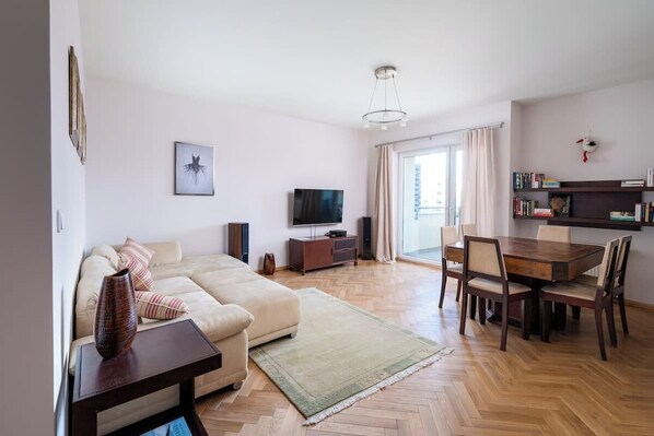 Een woonkamer met een bank, televisie en een eethoek.