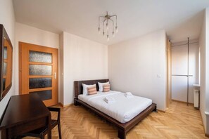 Een slaapkamer met een houten bed, een bureau en een deur met geëtste glaspanelen.