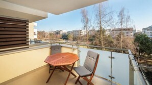 Varanda com mesa e cadeiras, vista para a paisagem urbana, e corrimão.