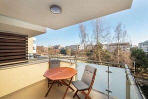 Een balkon met een tafel en stoelen, een uitzicht op de stad en een hekwerk.
