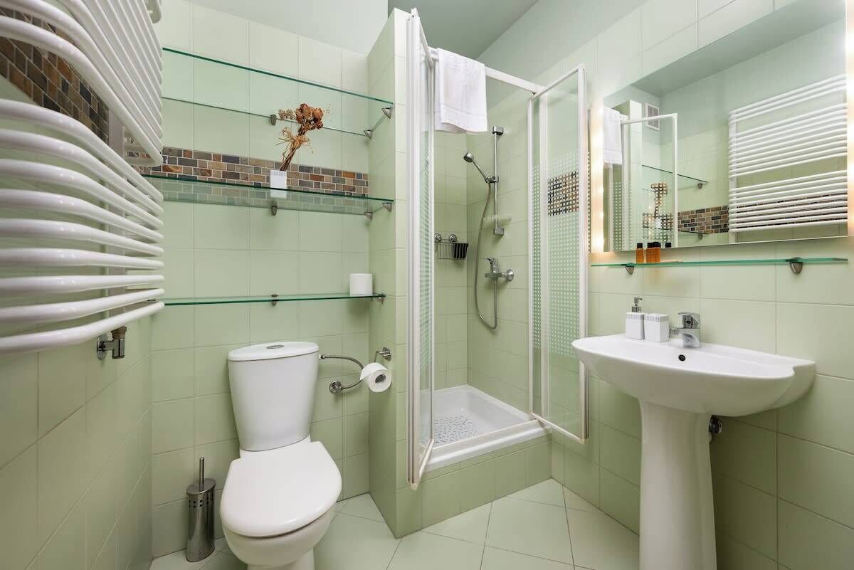 A bathroom with a toilet, glass shower enclosure, and a sink.