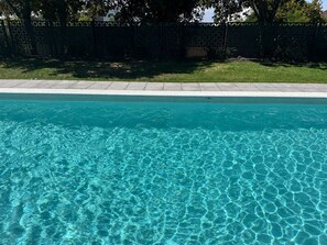 Une piscine à eau claire, avec un bord carrelé et un repère indiquant une profondeur de 1,4 mètre.