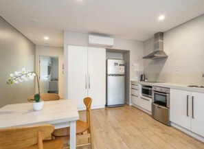 A modern kitchen with white cabinets, a stainless steel oven, and a built-in stove. - Coastal Escape | Heart of Nelson Bay | Family-Friendly Poolside Paradise (Nelson Bay)