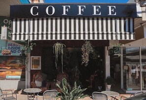 Un café doté d’un auvent rayé et proposant des places assises en extérieur.