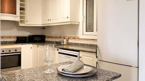 A kitchen with white cabinets, a microwave, a dishwasher, and a refrigerator. - Pink La Perla Apartment (Zenia, La)