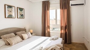 Habitación de hotel con cama, cortinas, mesita de noche, lámpara y decoración en la pared.