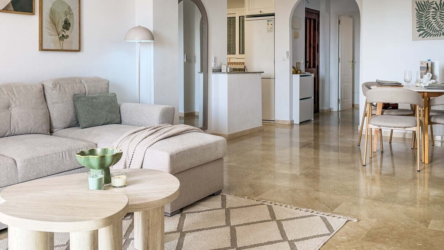 Ein Wohnzimmer mit einer Couch, zwei Beistelltischen, einem Couchtisch und einem gemusterten Teppich.