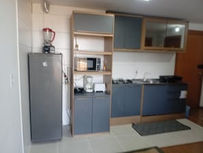 A compact kitchen with a grey refrigerator, a microwave, and a coffee maker on the countertop.