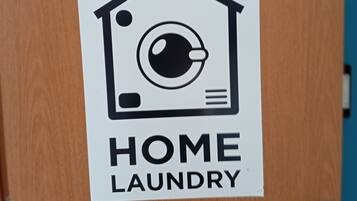 A door with a white sign that reads 'HOME LAUNDRY' and a smaller sign above it that says 'LAVANDERIA.'