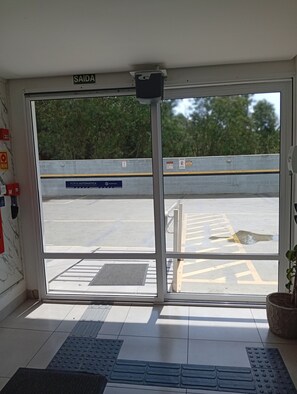 A hotel entrance with a glass door, a sign reading 'SAIDA', and a view of a parking area outside.